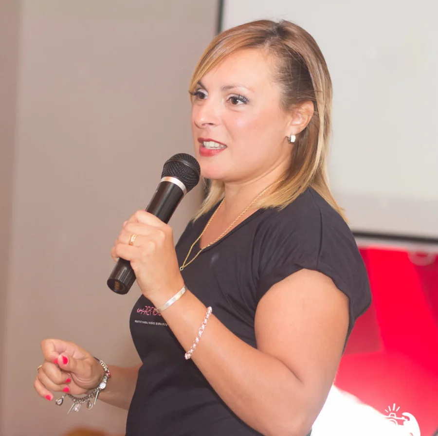 Caro Cuñé hablando con micrófono en un encuentro de EmPrendidas